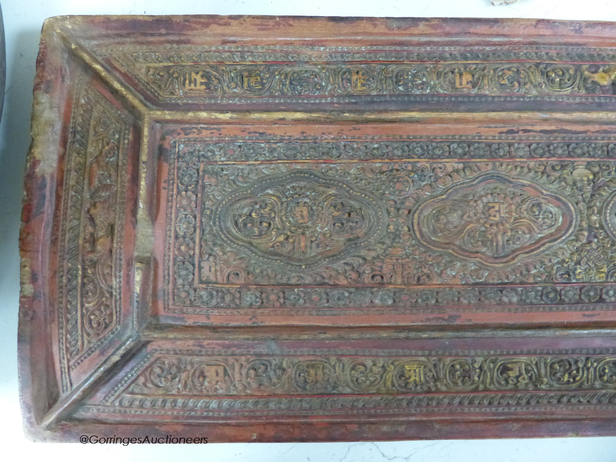 A 15th/16th century Tibetan carved and lacquered wood cover for a sutra box, 72 x 24cm